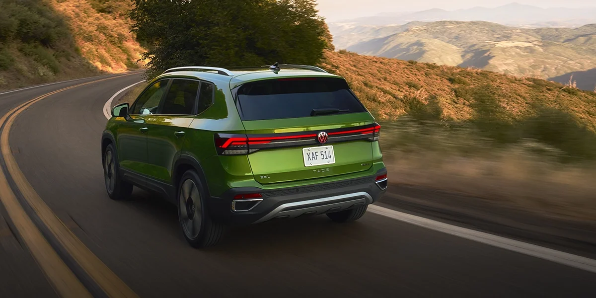 Volkswagen Taos in metallic green navigating mountain curves, showcasing its compact SUV agility and modern design.