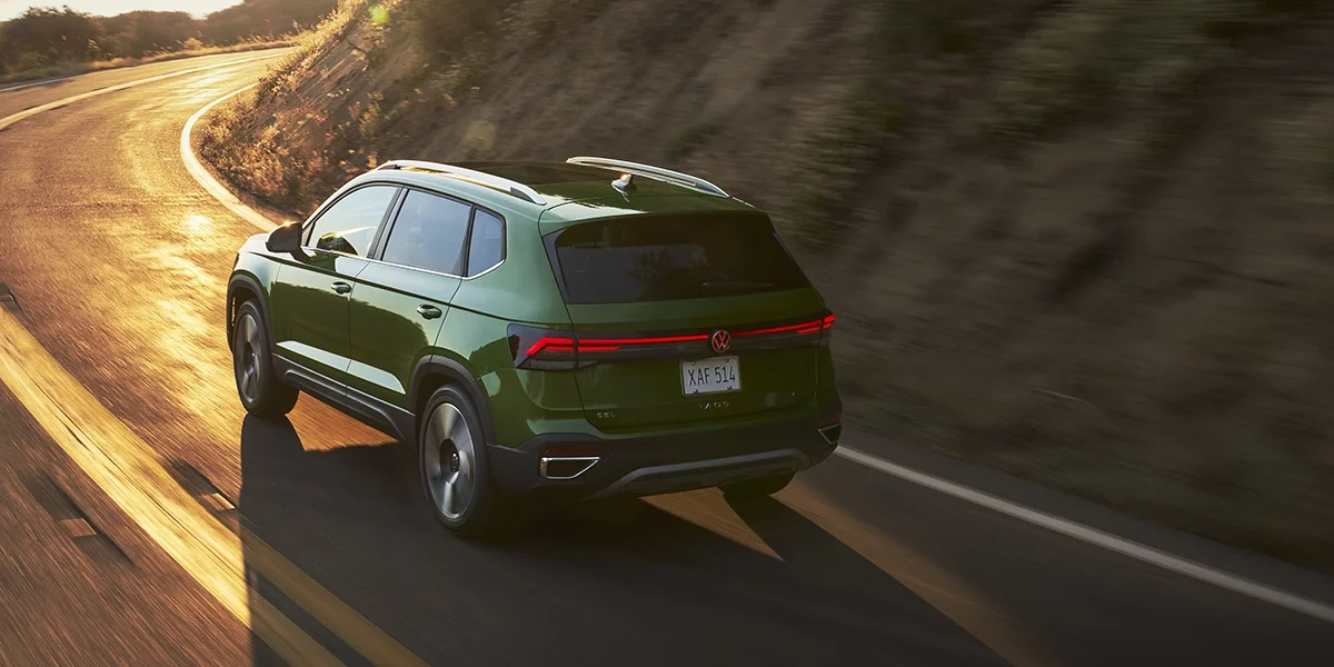 Rear three-quarter view of Volkswagen Taos in motion on mountain roads, highlighting its bold styling and adventure-ready performance.