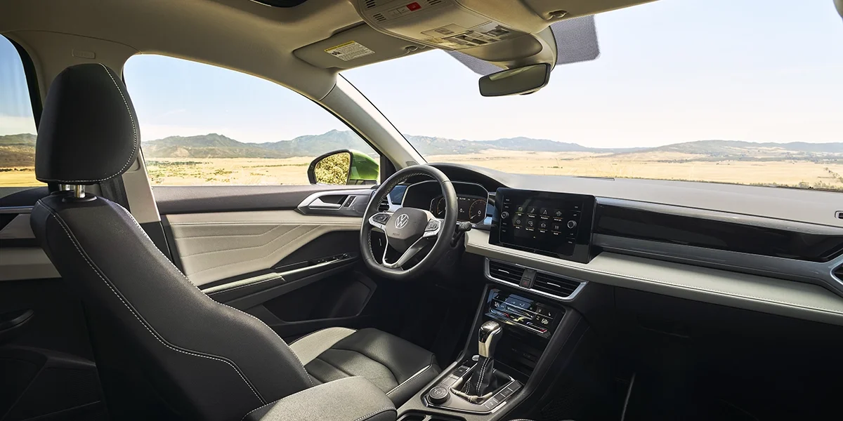 Volkswagen Taos interior showing the driver’s cockpit with digital display, touchscreen infotainment, and refined dashboard design.