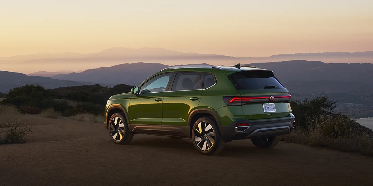 Volkswagen Taos parked at sunset with mountain views, emphasizing its sculpted body lines and LED taillight signature.